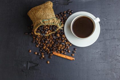 دانلود عکس دانه های قهوه در کیسه گونی قهوه ای با فنجان قهوه روی مشکی