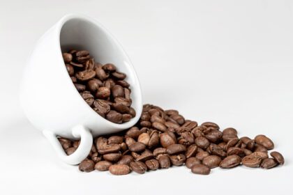 دانلود عکس دانه های قهوه در فنجان قهوه روی سفید