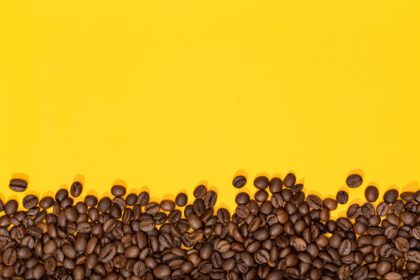 دانلود عکس دانه های قهوه روی حاشیه قهوه پس زمینه زرد با فضای کپی