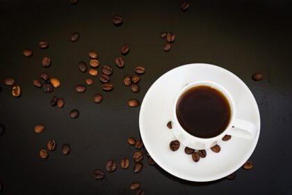 دانلود عکس فنجان قهوه و دانه های قهوه در پس زمینه تیره