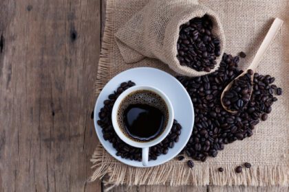 دانلود عکس فنجان قهوه و دانه های قهوه روی پس زمینه تخته چوبی قدیمی