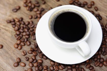 دانلود عکس فنجان قهوه و دانه های قهوه روی میز قهوه سیاه به رنگ سفید