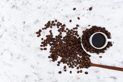 دانلود عکس فنجان قهوه و دانه های قهوه در نمای بالا پس زمینه سفید