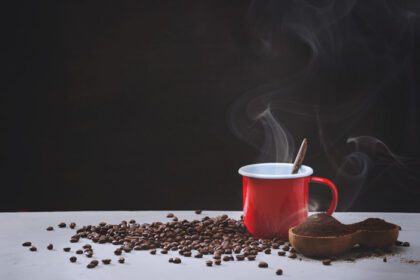 دانلود عکس فنجان قهوه قرمز و دانه های قهوه در نمای سمت سفید با