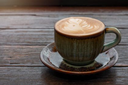 دانلود عکس قهوه در فنجان سبز روی میز چوبی در کافه