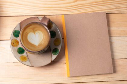 دانلود عکس لیوان قهوه و نوت بوک در پس زمینه چوبی