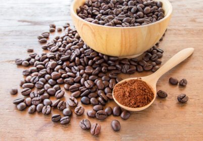 دانلود عکس پودر قهوه در قاشق چوبی و دانه های قهوه روی میز چوبی