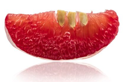 دانلود عکس نمای نزدیک از پالپ پوملو قرمز با دانه های جدا شده روی سفید