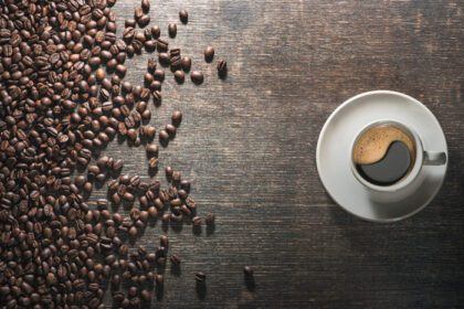 دانلود عکس فنجان قهوه با دانه های قهوه روی میز قدیمی