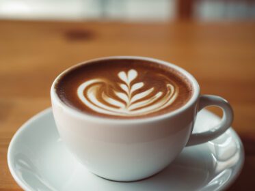 دانلود عکس فنجان قهوه داغ سرو شده روی میز چوبی در کافه