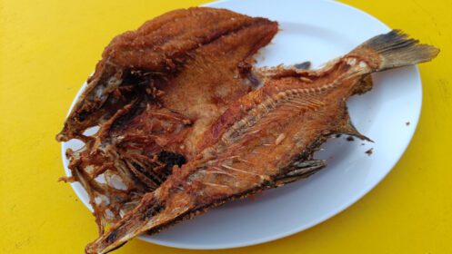 دانلود عکس ماهی سرخ شده خوشمزه آسیایی سرو شده روی میز زرد غذای تایلندی