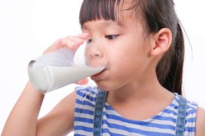 دانلود عکس دختر بچه ناز در حال نوشیدن شیر از لیوان جدا شده روی