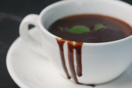 دانلود عکس خامه شکلاتی تیره در فنجان قهوه روی میز