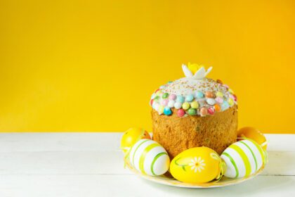 دانلود عکس کیک عید پاک با تخم مرغ های رنگ شده روی بشقاب در یک میز سفید