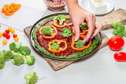 دانلود عکس دست های زن قرار دادن تکه های بروکلی روی پیتزا مفهومی از