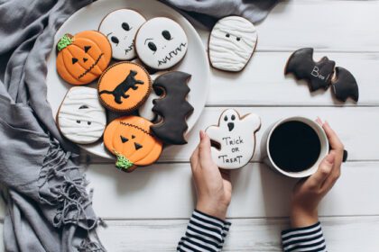 دانلود عکس زن در حال آماده شدن برای هالووین در حال نوشیدن قهوه با شیرینی زنجبیلی
