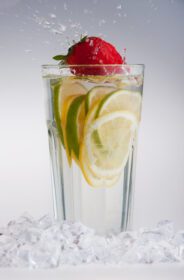 دانلود عکس لیوان نوشیدنی با تکه های یخ و میوه ها روی سفید