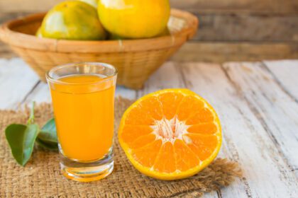 دانلود عکس لیوان آب پرتقال تازه فشرده روی میز چوبی