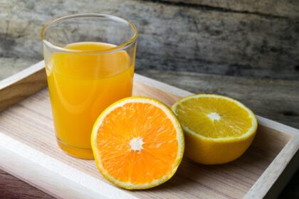 دانلود عکس لیوان آب پرتقال روی میز چوبی نوشیدنی تازه