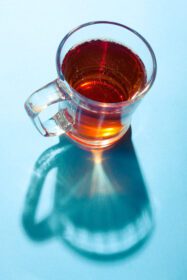 دانلود عکس لیوان چای در پس زمینه آبی زیر نور خورشید