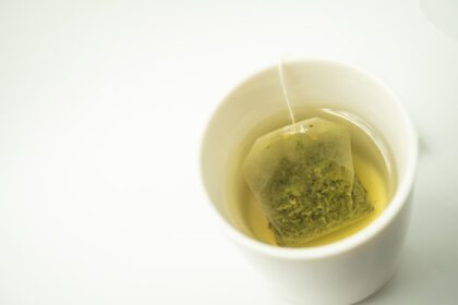 دانلود عکس چای سبز کیسه ای در یک فنجان چای سبز معطر روی سفید