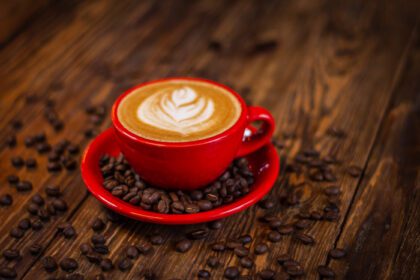 دانلود عکس قهوه کاپوچینوی داغ در فنجان قرمز با نعلبکی روی چوب