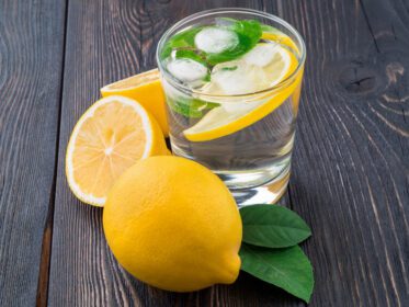 دانلود عکس لیموناد در لیوان یک لیمو نیم برگ تازه روی تاریکی
