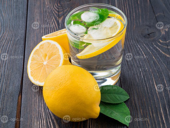 دانلود عکس لیموناد در لیوان یک لیمو نیم برگ تازه روی تاریکی
