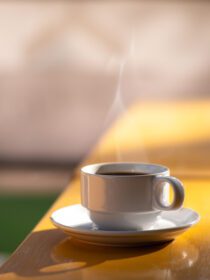 دانلود عکس قهوه داغ صبحگاهی روی میز چوبی زرد در روز روشن