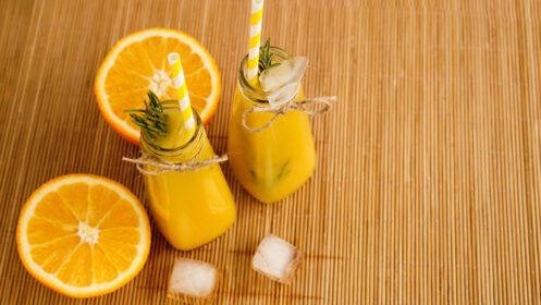 دانلود عکس بطری های آب پرتقال و نی های کاغذی نوشیدنی یخی در یک روز آفتابی