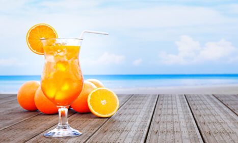 دانلود عکس آب پرتقال در لیوان شفاف با تکه های یخ و پرتقال