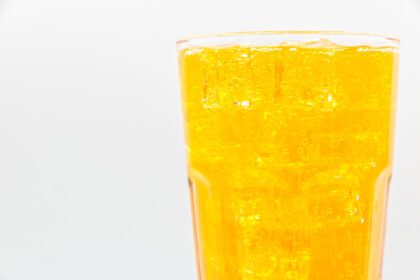 دانلود عکس آب گازدار نارنجی با یخ در شیشه روی پس زمینه سفید