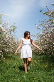 دانلود عکس زن جوان قفقازی در حال لذت بردن از گل دادن درختان سیب