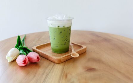 دانلود عکس فنجان پلاستیکی چای سبز سرد روی میز چوبی