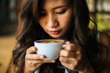 دانلود عکس پرتره زن آسیایی خندان در کافه کافی شاپ استراحت کنید