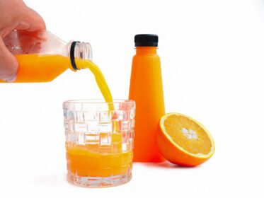 دانلود عکس آب پرتقال را در یک ظرف شیشه ای بر روی زمینه سفید بریزید