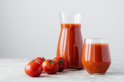 دانلود عکس گوجه فرنگی خام و لیوان نوشیدنی تازه جدا شده روی سفید