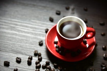 دانلود عکس فنجان قرمز قهوه با بخار جریانی و دانه قهوه