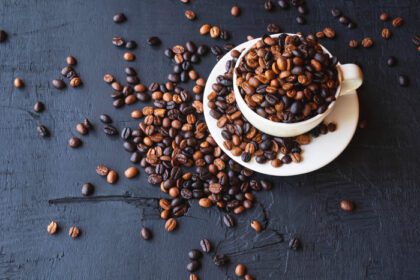 دانلود عکس دانه های قهوه برشته شده در یک فنجان قهوه