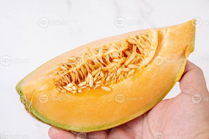 دانلود عکس خربزه برش خورده در دست بالای پس زمینه سفید
