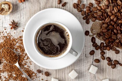 دانلود عکس بالا مشاهده یک فنجان قهوه داغ با دانه های کامل و آسیاب شده