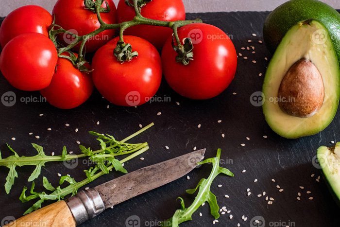 دانلود عکس گوجه فرنگی و آووکادو روی میز سیاه از نزدیک رنگارنگ