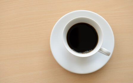 دانلود عکس نمای بالای یک فنجان قهوه داغ روی میز چوبی