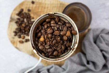 دانلود عکس دانه های قهوه کامل در یک چرخ قهوه برقی نمای بالا