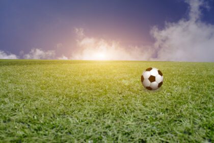 دانلود عکس توپ در زمین سبز با غروب آسمان آبی فوتبال
