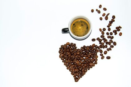 دانلود عکس یک فنجان اسپرسو با کف در کنار دانه های قهوه چیده شده