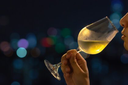 دانلود عکس شخصی در حال بو کشیدن شراب سفید در لیوان برای مزه کردن شراب