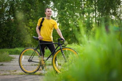دانلود عکس مرد جوانی برای استراحت با دوچرخه خود در پارکی عمومی ایستاد