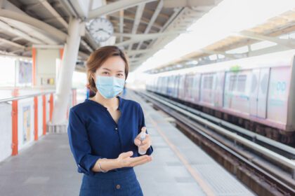 دانلود عکس زن آسیایی در ایستگاه منتظر قطار است که اسپری می کند