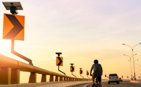 دانلود عکس نمای پشت مردی که کلاه ایمنی به سر دارد دوچرخه سواری روی منحنی